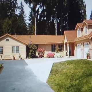 A serene residential house surrounded by greenery, featuring a spacious driveway and well-maintained garden.