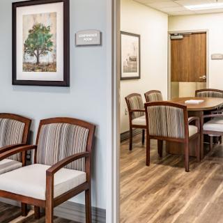 A well-designed waiting area leading to a meeting room, featuring comfortable wooden chairs and a calming decor.