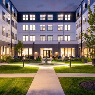 A beautifully illuminated building with a landscaped courtyard at night.