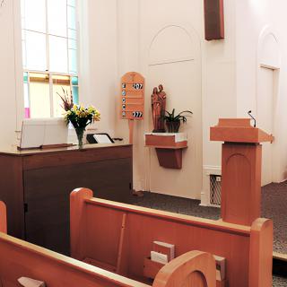 Interior of a church with pews, a podium, and an altar.