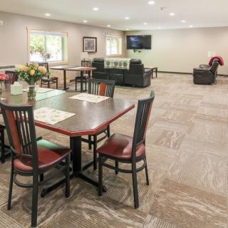 A spacious community room with dining tables, chairs, and a television.