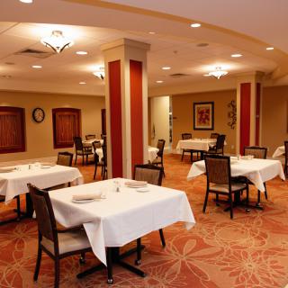 An empty restaurant dining room with neatly arranged tables and chairs.