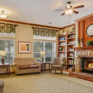 A cozy living room with a fireplace and bookshelves, featuring comfortable seating and elegant decor.