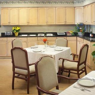 A neatly arranged dining area within a kitchen, featuring wooden cabinets and a table set for four.