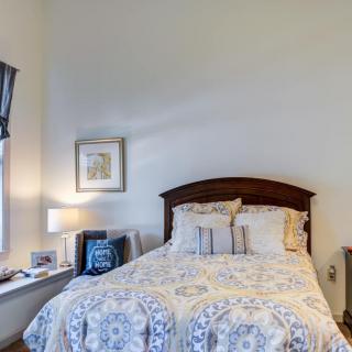 A cozy bedroom with a neatly made bed, bedside lamp, and wall art.