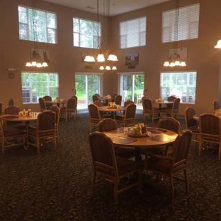 A cozy dining area with multiple round tables and chairs, illuminated by warm lighting.