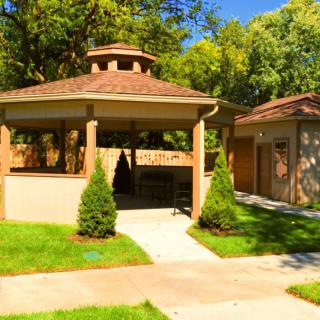 A charming gazebo surrounded by lush greenery and a well-maintained garden path.