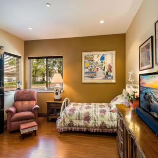 A cozy bedroom with a single bed, armchair, and warm decor.