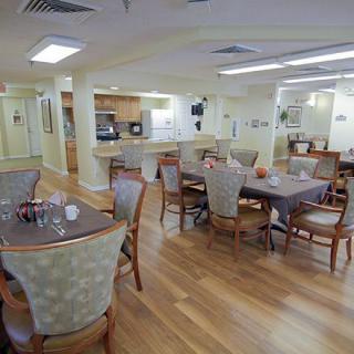 A cozy dining area with wooden floors and neatly arranged tables and chairs.