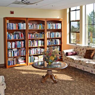 A cozy reading area with bookshelves filled with books, comfortable sofas, and a round table in a well-lit room.