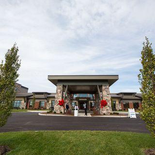 A wide-angle view of a modern building entrance with landscaped surroundings and clear skies.