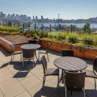 Rooftop patio with tables and chairs overlooking a city skyline.