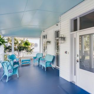 A charming porch with blue and white decor, featuring wicker furniture and plants.