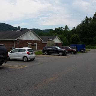 A view of a parking lot in a residential area, surrounded by mountains under a cloudy sky.