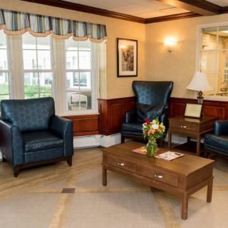 A cozy living room with leather chairs and a wooden table adorned with flowers.