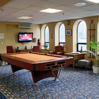 A cozy game room featuring a billiards table, comfortable seating, and a television.