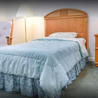 A cozy bedroom with a neatly made bed, bedside lamp, and nightstand.