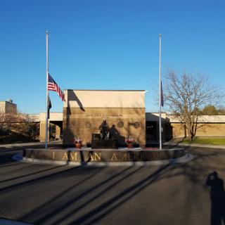 Flags flying at half-mast in front of a building on a clear day.