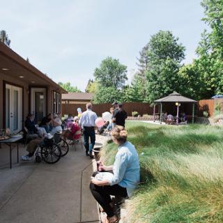 A serene outdoor area in a community setting, with residents engaging in activities amidst lush greenery.
