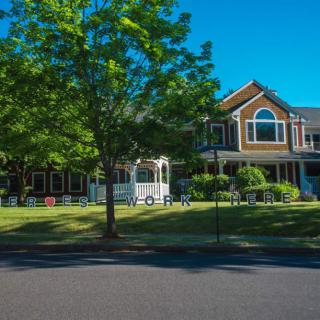A suburban house with a well-maintained lawn and tree on a sunny day.