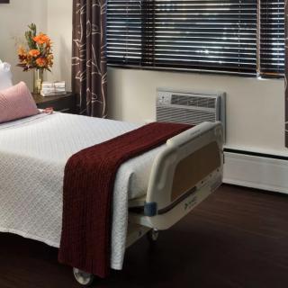 A neatly arranged hospital room with a single bed and flowers by the window.