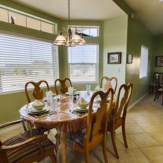 A sunlit dining room with a set table and elegant wooden chairs.