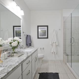 A modern bathroom with a marble countertop and glass-enclosed shower.
