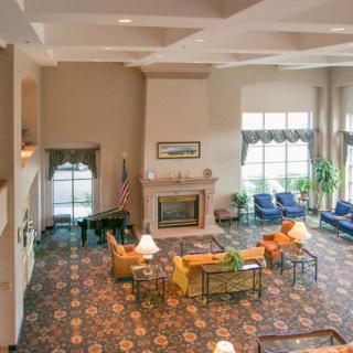 A spacious hotel lobby featuring a cozy fireplace, comfortable seating arrangements, and large windows.