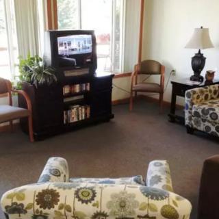 A cozy living room with a television, patterned chairs, and a bookshelf.
