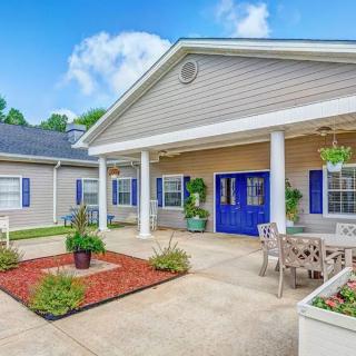 A charming residential house exterior with a landscaped patio and blue doors.