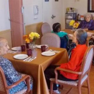 A group of senior individuals gathered around a table in a dining area, enjoying a meal together.