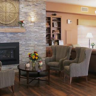 A cozy living room with striped chairs, a glass coffee table, and a stone fireplace.