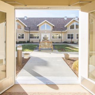 View of a pathway leading to a building with large windows and a courtyard.