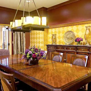 A warmly decorated dining room with a wooden table, chairs, and chandelier.