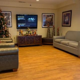 A cozy living room with comfortable seating, a decorated Christmas tree, and a wall-mounted television.