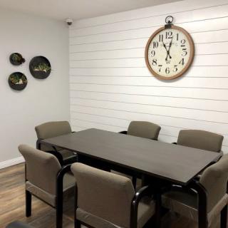 A modern dining area featuring a sleek table, six chairs, and decorative wall elements with a large clock.