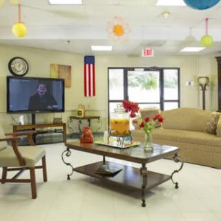 A cozy living room with comfortable seating, a television, and colorful decorations.