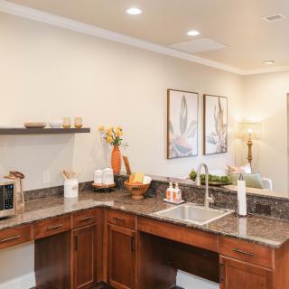 A modern kitchen with wooden cabinets, a large countertop, and various decor items.