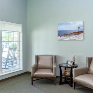 A cozy waiting room with two chairs, a small table, and a window providing natural light.
