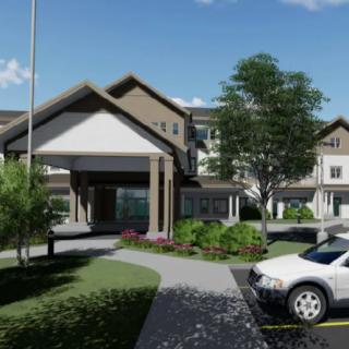 A modern building with a landscaped entrance and a parking area featuring cars.
