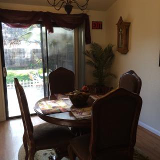 A cozy dining room with a round table and chairs, featuring a large sliding glass door leading to the garden.