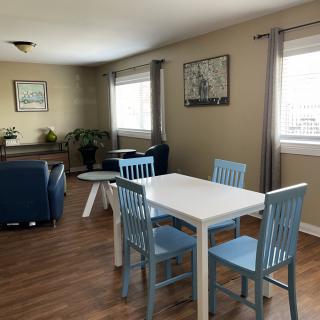 A cozy living and dining area with blue chairs and a wooden floor.