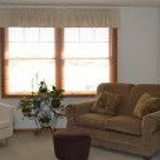 A cozy living room with a sofa, chair, and a large window with curtains.