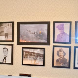 A collection of vintage photographs displayed in black frames on a wall, showcasing a variety of historical figures and scenes.
