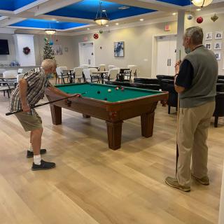 Two people playing billiards in a recreational room.