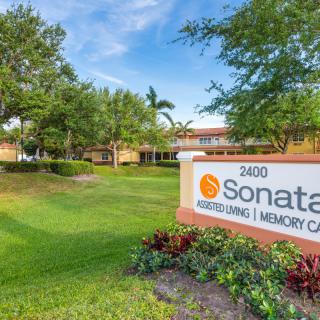 A landscaped outdoor area with a sign for Sonata Memory Care Center.