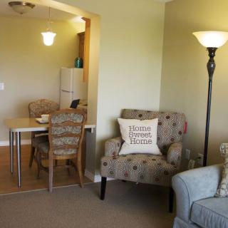 A cozy living room with a comfortable chair and floor lamp next to a dining area.
