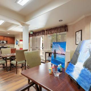 A cozy indoor space featuring a living area with a kitchen, showcasing artworks and comfortable seating.