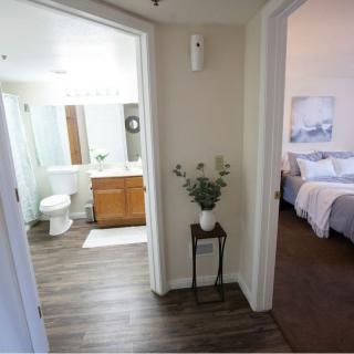 A modern home interior featuring a hallway with a view into a bathroom and bedroom.