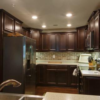 A modern kitchen with dark cabinets and stainless steel appliances.